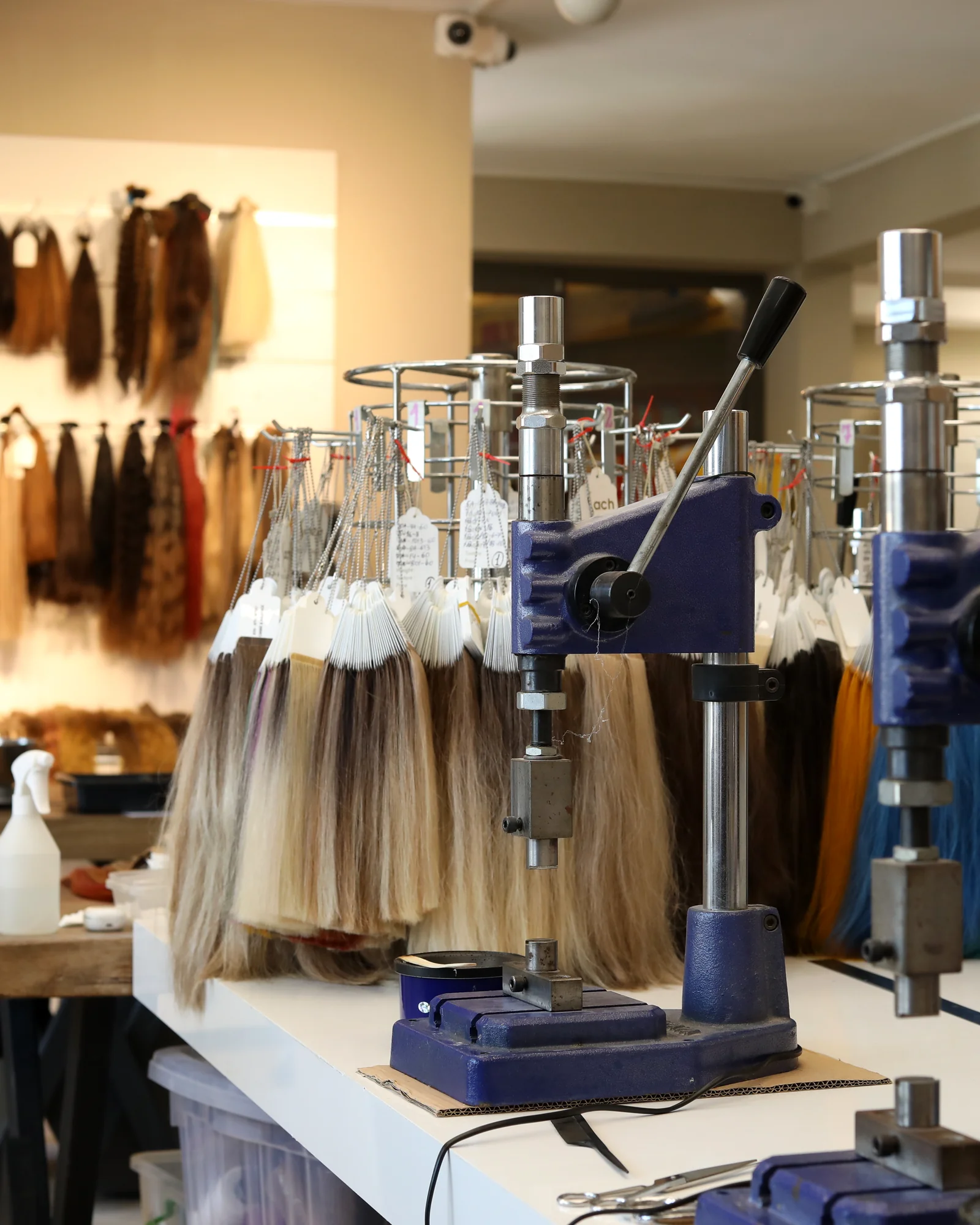 Hair extension production presses and classified human-hair samples at the HairExtensionsTR facility in Türkiye.
